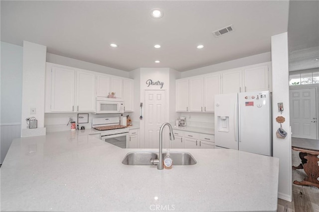 kitchen with sink, white cabinets, white appliances, and kitchen peninsula