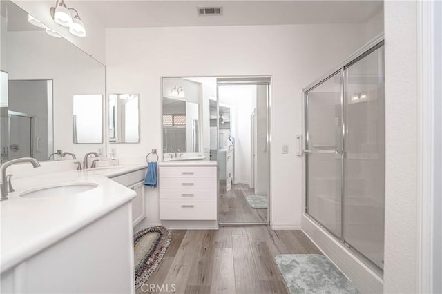 bathroom featuring wood-type flooring, a shower with door, and vanity