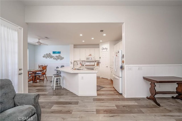 kitchen with sink, light wood-type flooring, white appliances, and white cabinets