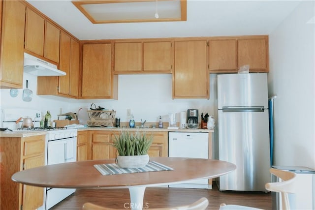 kitchen featuring white appliances, wood finished floors, a sink, light countertops, and under cabinet range hood