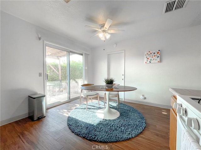 dining area with ceiling fan, visible vents, baseboards, and wood finished floors