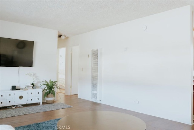 living room featuring a heating unit, a textured ceiling, and wood finished floors