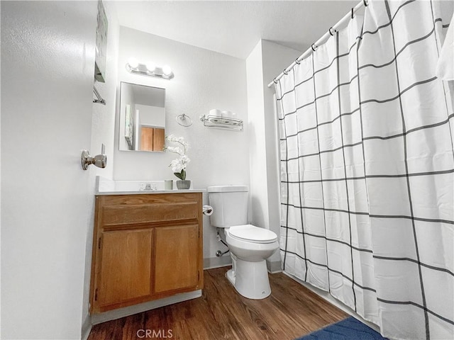 bathroom with wood-type flooring, walk in shower, vanity, and toilet