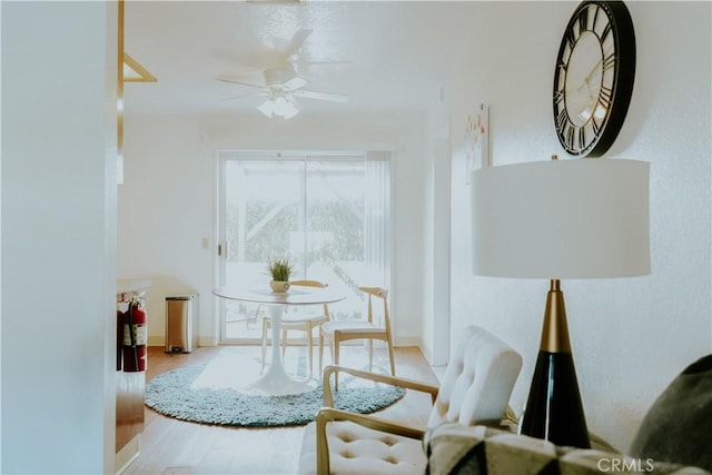 living area featuring baseboards, ceiling fan, and wood finished floors