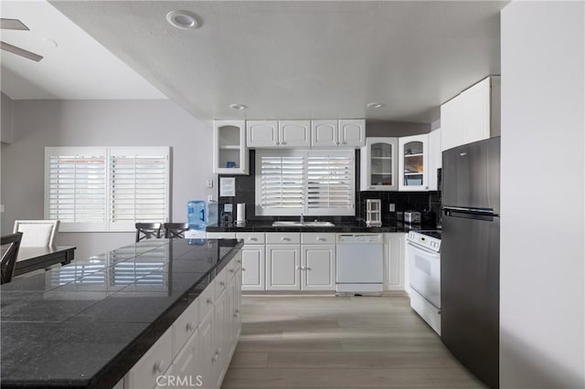 kitchen featuring white cabinetry, sink, tasteful backsplash, light hardwood / wood-style flooring, and white appliances