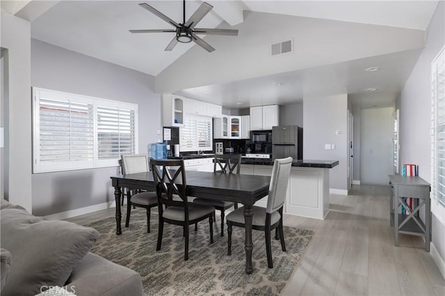 dining area with lofted ceiling with beams, ceiling fan, and light wood-type flooring