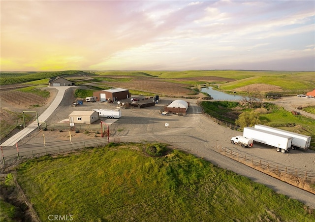 aerial view at dusk featuring a water view and a rural view