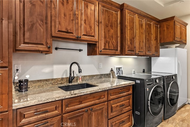 clothes washing area featuring cabinets, sink, washing machine and clothes dryer, and light tile patterned floors