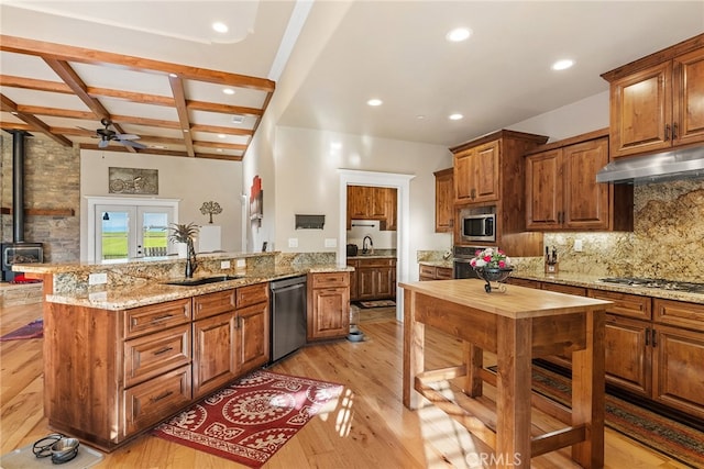 kitchen with beamed ceiling, sink, light hardwood / wood-style flooring, and stainless steel appliances