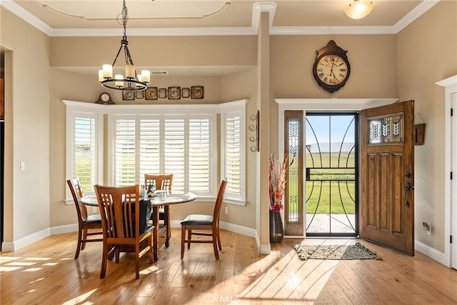 foyer entrance with a chandelier, crown molding, and light wood-type flooring