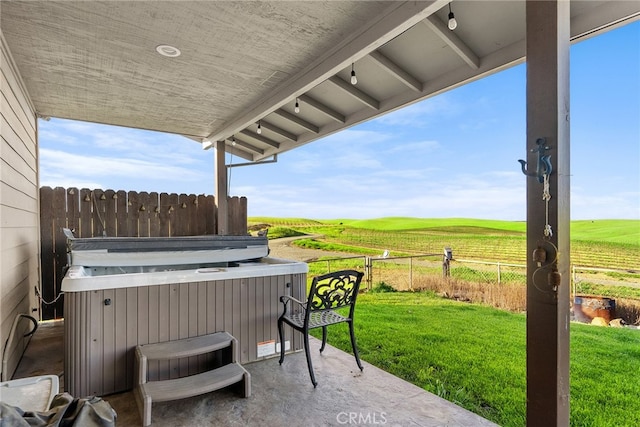 view of patio with a hot tub and a rural view