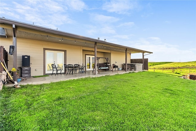 rear view of house with a yard, a patio, and a rural view