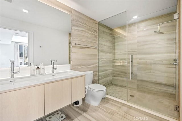 bathroom with an enclosed shower, vanity, and toilet