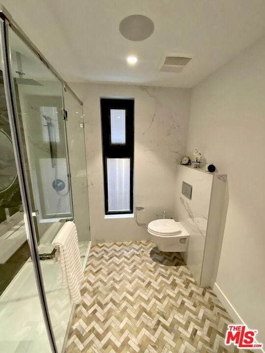 bathroom featuring toilet and a shower with shower door