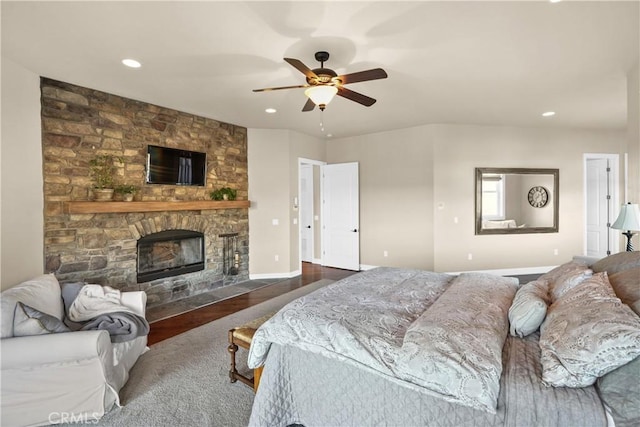 bedroom with ceiling fan, dark hardwood / wood-style flooring, and a stone fireplace