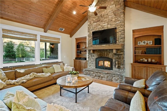 living room with ceiling fan, beam ceiling, wood ceiling, a stone fireplace, and high vaulted ceiling