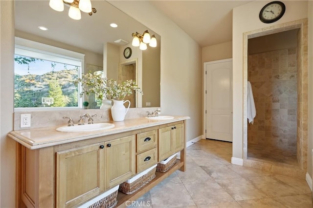 bathroom with an inviting chandelier, tile patterned flooring, tiled shower, and vanity