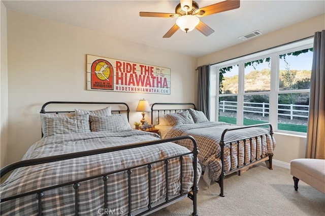 bedroom with ceiling fan, multiple windows, and light carpet