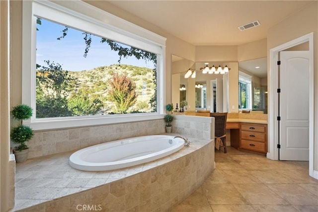 bathroom with tiled bath, a wealth of natural light, and vanity