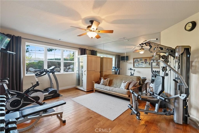 exercise area with ceiling fan and light wood-type flooring