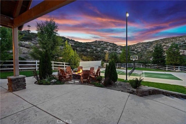 patio terrace at dusk featuring a mountain view and a fire pit