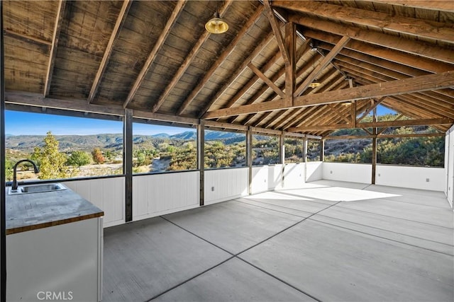 unfurnished sunroom with vaulted ceiling, a mountain view, and sink