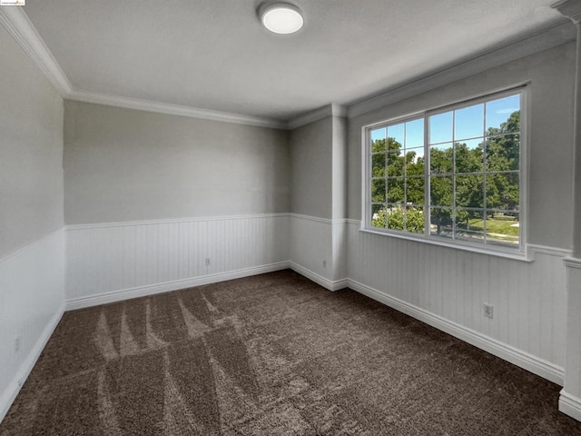 spare room with ornamental molding, wooden walls, and dark colored carpet