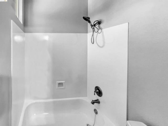 bathroom featuring washtub / shower combination and toilet