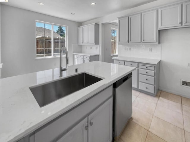 kitchen with sink, backsplash, stainless steel dishwasher, gray cabinets, and light tile patterned floors