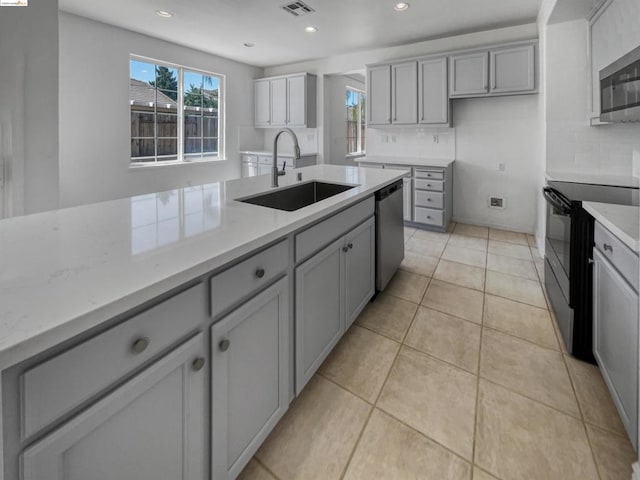 kitchen with gray cabinetry, sink, stainless steel appliances, light stone counters, and light tile patterned floors