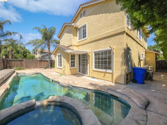 back of property featuring a patio area and a swimming pool with hot tub