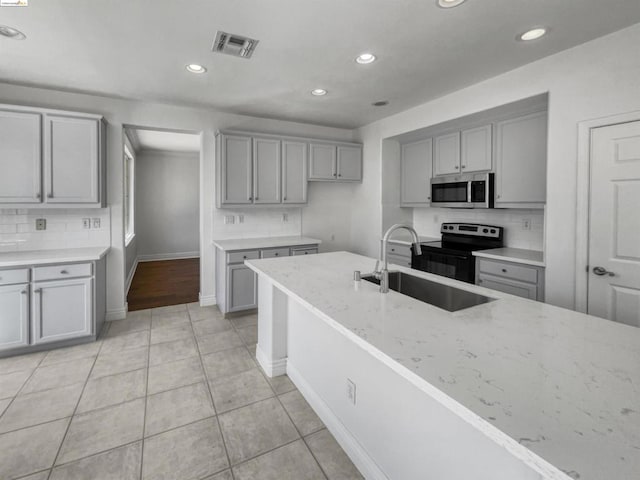 kitchen with gray cabinetry, range with electric cooktop, light stone countertops, sink, and light tile patterned floors