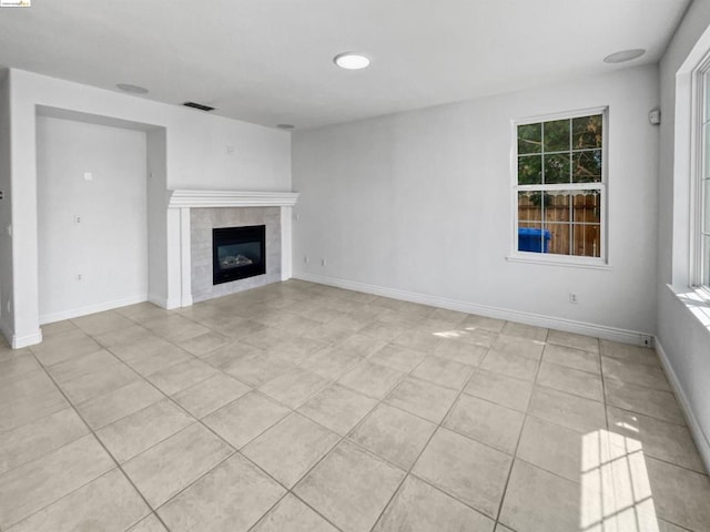 unfurnished living room with a tiled fireplace and light tile patterned floors