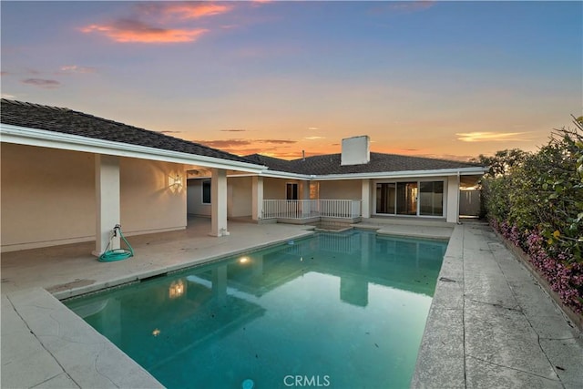 pool at dusk featuring a patio area