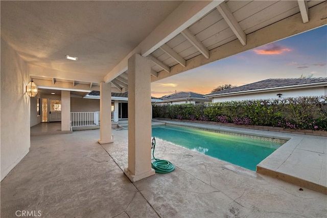 pool at dusk with a patio area