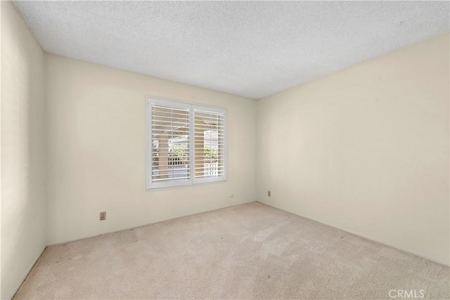 unfurnished room with light colored carpet and a textured ceiling