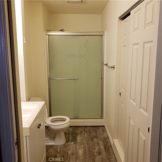 bathroom with an enclosed shower, hardwood / wood-style flooring, vanity, and toilet