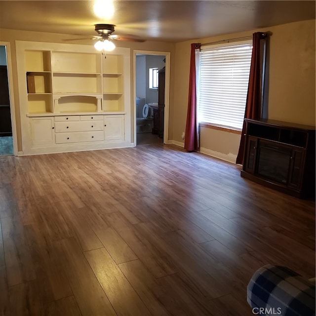 unfurnished living room with wood-type flooring, built in shelves, and ceiling fan