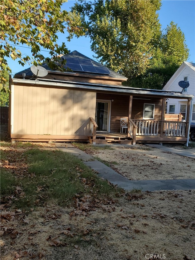 back of house with a porch and solar panels