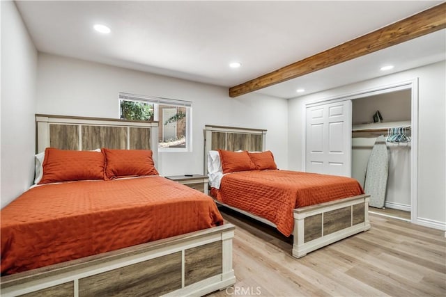 bedroom featuring beamed ceiling, light hardwood / wood-style flooring, and a closet