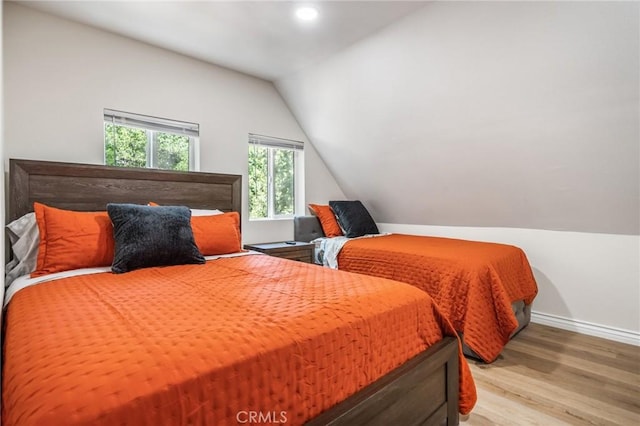 bedroom featuring light hardwood / wood-style floors and lofted ceiling