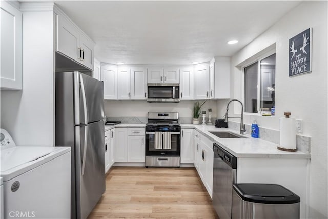 kitchen featuring sink, light wood-type flooring, washer / dryer, white cabinetry, and stainless steel appliances