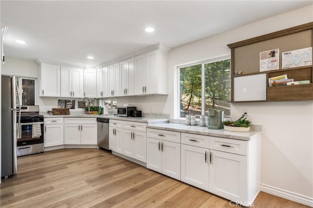 kitchen featuring white cabinets, light wood-type flooring, and appliances with stainless steel finishes