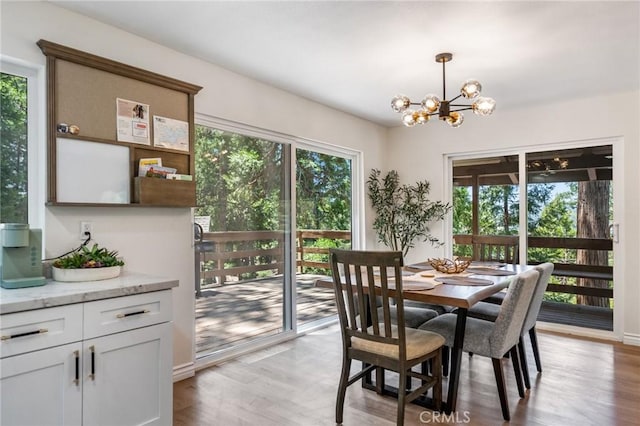 dining space with a healthy amount of sunlight, a notable chandelier, and light wood-type flooring