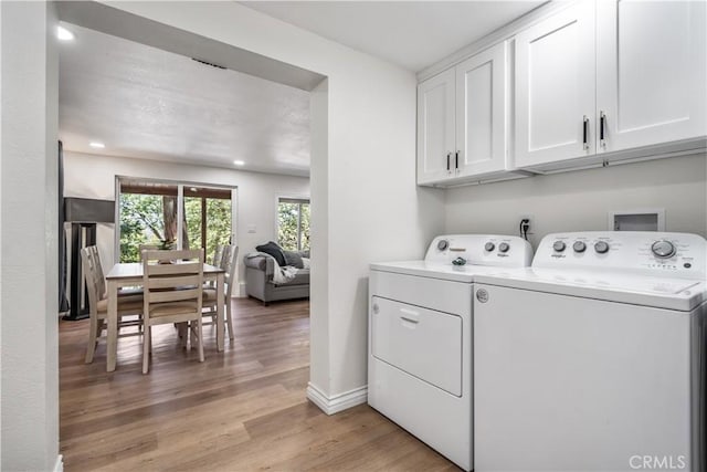 laundry room with cabinets, light hardwood / wood-style flooring, and washer and clothes dryer