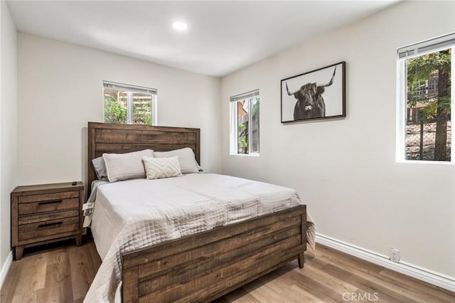 bedroom with multiple windows and light hardwood / wood-style floors