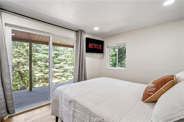 bedroom featuring access to exterior, light wood-type flooring, and multiple windows