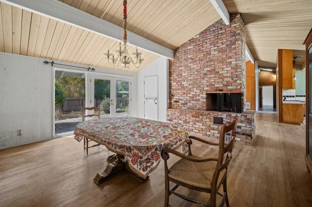 dining space featuring a brick fireplace, wood-type flooring, vaulted ceiling with beams, and french doors