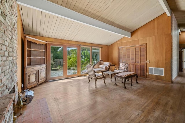 living area with light hardwood / wood-style flooring, vaulted ceiling with beams, and wooden walls