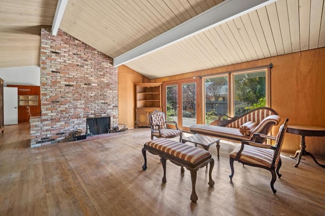 interior space featuring vaulted ceiling with beams, wooden walls, hardwood / wood-style floors, and a brick fireplace